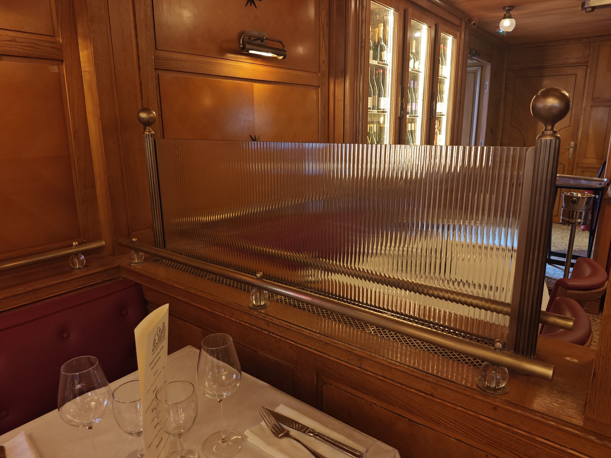 Chapelière en laiton vieilli et verre flûté trempé Chapelière design en laiton vieilli avec verre flûté trempé dans le restaurant Le Stella